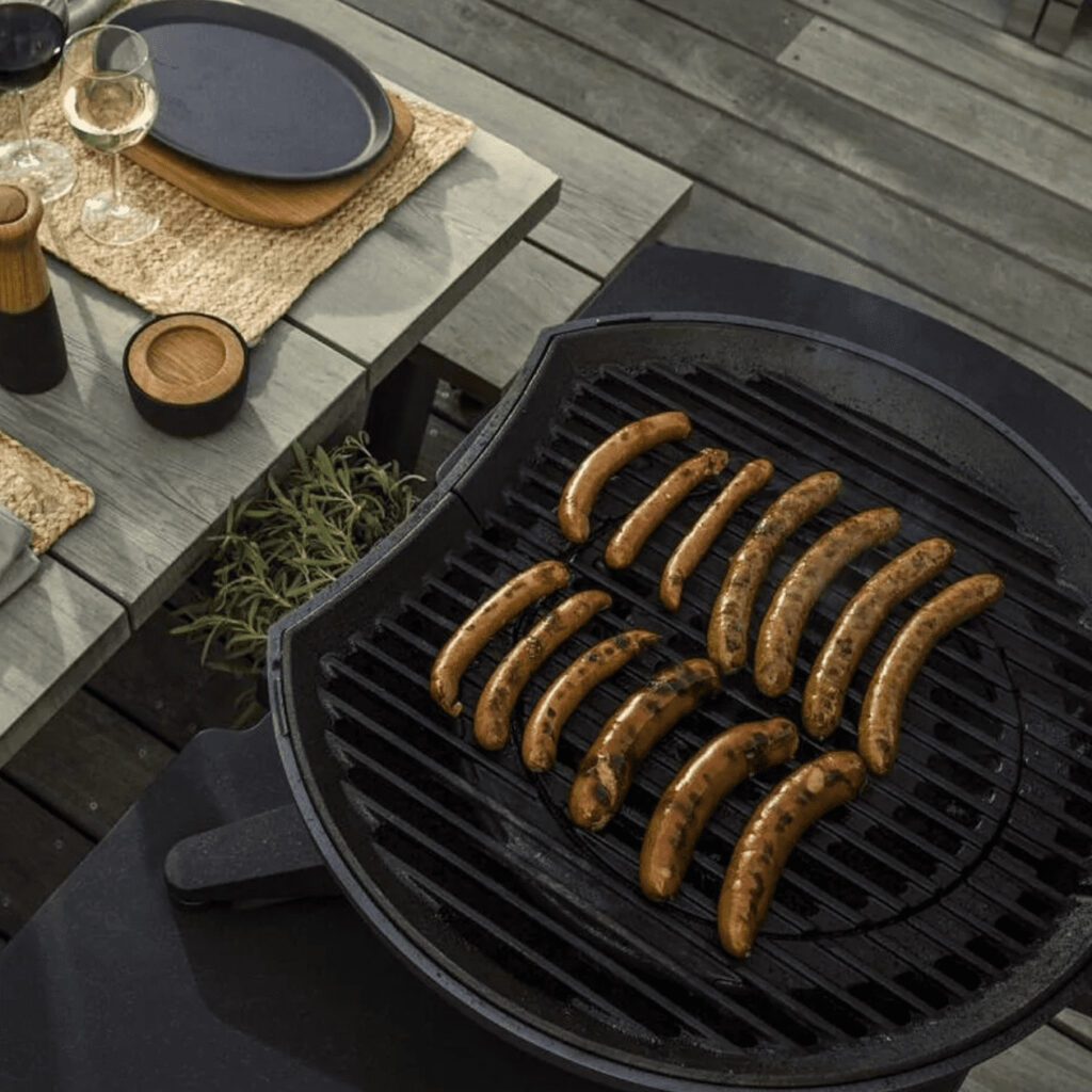 Der Morsø Forno Gas belegt mit Grillwürstchen auf Holzboden.