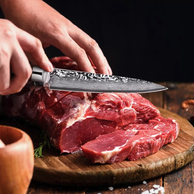 Ein Paar Hände schneiden mit einem scharfen Messer ein großes Stück Fleisch.