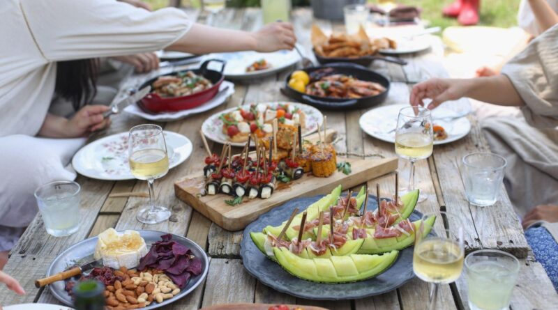 Esstisch auf der Terrasse, gedeckt mit Grillgut und Weingläsern.